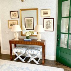 a living room with green doors and pictures on the wall, two stools in front of a table