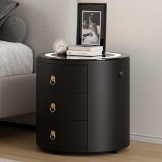 a night stand with two drawers and an alarm clock on the top, next to a bed