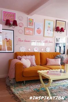 a living room with pink walls and pictures on the wall above the orange couches