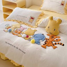 a bed with winnie the pooh and tigger pillows on it, along with two stuffed animals