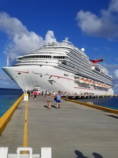 a cruise ship docked at the dock with people walking on it's walkways