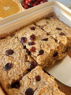 some oatmeal bars are in a pan with oranges and cranberries