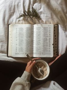 an open book on top of a bed next to a bowl of oatmeal