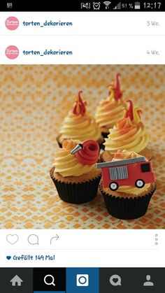 some cupcakes with frosting and firetruck decorations on them sitting on a table