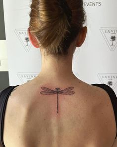 a woman with a dragonfly tattoo on her back