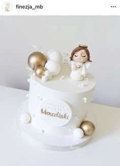 there is a white cake with gold decorations on the top, and an angel figurine atop it