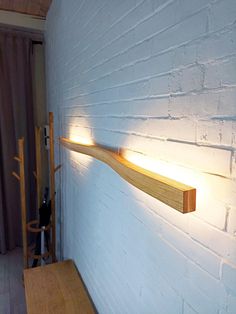 a white brick wall with a wooden shelf and two lights on it's sides