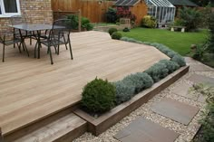 a wooden deck surrounded by plants and gravel