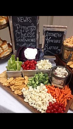 an assortment of different types of food on a table with chalkboards and signs in the background