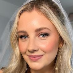 a woman with blonde hair wearing a veil and smiling at the camera while she is looking into the camera