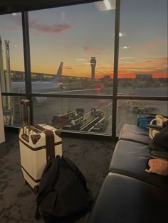 an airport terminal with luggage on the floor and a view of the tarmac at sunset