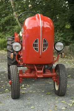 an old red tractor is parked on the gravel