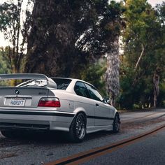 a silver car parked on the side of a road next to some trees and grass