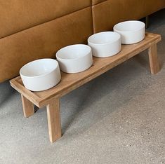 three white bowls are sitting on a wooden table in front of a brown leather couch