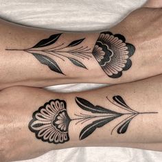 two people with matching tattoos on their legs, both have black and white flowers in them