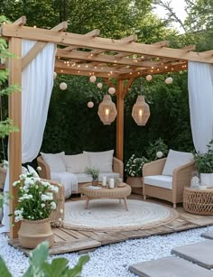 an outdoor living area with wicker furniture and lights on the ceiling, surrounded by greenery