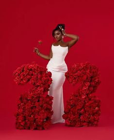 a woman in a white dress standing next to red flowers