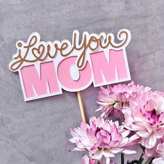 a bouquet of pink flowers sitting next to a sign that says i love you mom