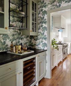 a kitchen with green and white wallpaper and wooden flooring, built - in wine cellar