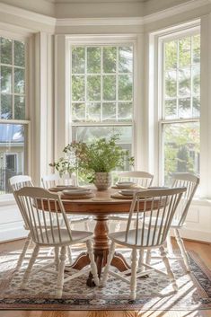 a dining table with four chairs and a potted plant in the middle of it