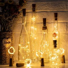 several bottles with lights in them sitting on a table