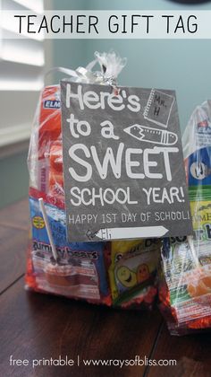 a teacher gift tag on top of a bag filled with school supplies and the words, here's to a sweet school year happy 1st day of school