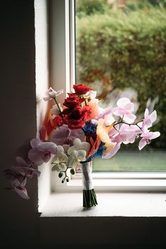 a bouquet of flowers sitting on top of a window sill next to a window