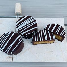 four pieces of chocolate covered cake sitting on top of a white marble counter next to a corkscrew