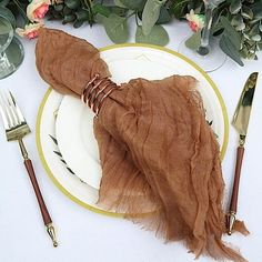 a white plate topped with a piece of cloth next to two forks and knifes