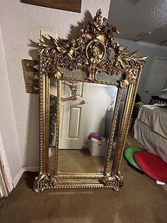 an ornate gold framed mirror sitting on the floor