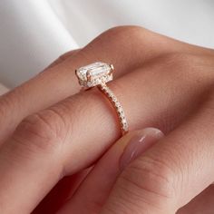 a woman's hand holding an engagement ring with a diamond on the top and side