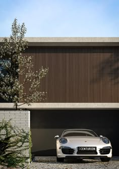 a white sports car parked in front of a building with wooden slats on the side