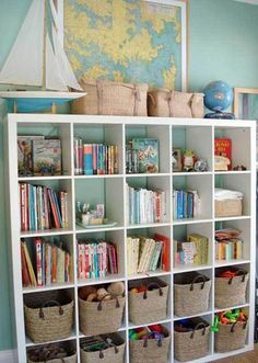 a bookshelf filled with lots of books next to a wall mounted ship on the wall