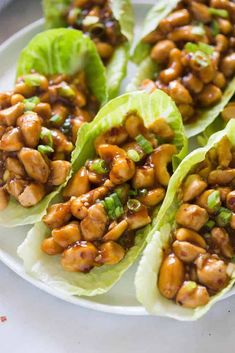 lettuce wraps filled with chicken and sauce on a white plate, ready to be eaten