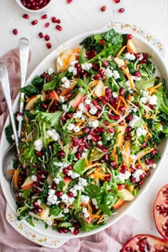 a salad with pomegranate, carrots and feta cheese in a white bowl