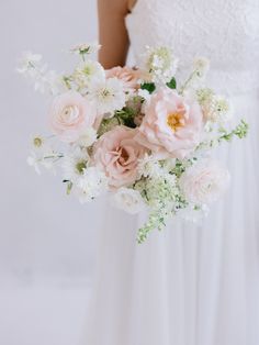 a bride holding a bouquet of pink and white flowers