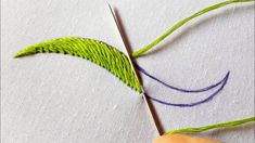 someone is using scissors to cut the green thread off of their handmade piece of cloth