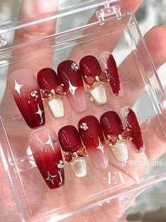 red and white nails with gold accents on the tip of each nail are displayed in a clear case