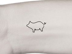 a small pig tattoo on the left wrist is shown in black ink, with an outline of a pig