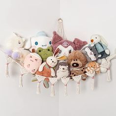 a bunch of stuffed animals sitting on top of a white shelf with tassels