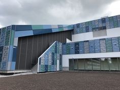 a large building with many windows next to a parking lot in front of it on a cloudy day