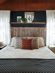 a bed with two pillows on top of it and curtains hanging over the headboard