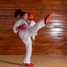 a woman is practicing karate kicking with red gloves