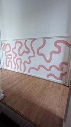 a white and pink painting on the wall in a room with wood flooring next to stairs