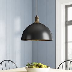 a bowl of fruit sitting on top of a table next to a light hanging over it