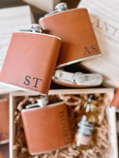 two leather flasks in a gift box with personalized tags on them,