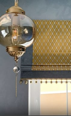 a light fixture hanging from the side of a window next to a yellow and white curtain