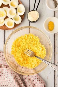 an image of eggs and other ingredients in a bowl on a white wooden table with utensils