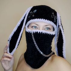 a woman wearing a black and white crochet mask with chains on her face