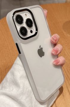 a woman's hand holding an iphone case on top of a wooden table